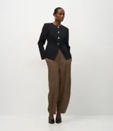 Blazer de sastrería estructurado en tejido crepe, con cuello redondo, cierre frontal con botones metálicos, bolsillos embutidos y mangas largas. Presenta un corte entallado que define la silueta.