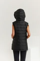 Chaleco negro oversize con capucha forrada en tela gamuzada, cierre metálico YKK, bolsillos laterales y tancas regulables en el ruedo.