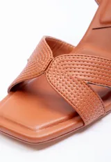 Sandalia alta de símil cuero negro con taco geométrico de 7.5 cm. Posee tiras cruzadas en el empeine con diseño pespuntado y tira ajustable con hebilla en el tobillo.