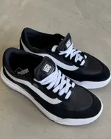 Championes Vans modelo Ultrarange 2.0 SE, color negro con detalles en blanco. Presentan un diseño moderno con entresuela amortiguada, cordones blancos y estructura reforzada en el talón. Combinan materiales textiles y gamuza para mayor durabilidad y respirabilidad.