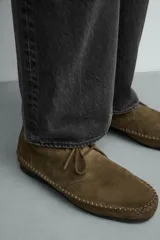 Zapato tipo derby de cordones, confeccionado en piel con acabado de serraje. Presenta costuras decorativas en el contorno de la suela, horma redonda y suela de goma Vibram.