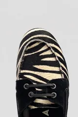 Mocasines tipo náuticos de cuero con estampado animal print de cebra y detalles en negro. Cuentan con cordones y ojales metálicos.