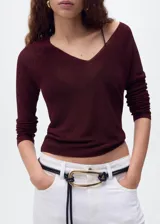Jersey de punto fino con acabado brillante de lúrex, cuello en pico y manga larga. Presenta un diseño recto y entallado.