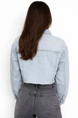 Campera de jean estilo crop top, de color celeste claro, con cierre frontal de botones metálicos, cuello clásico y bolsillos delanteros con solapa.