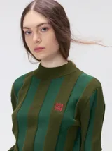 Sweater de punto con cuello polera, diseño a rayas verticales en tonos azules y logo bordado en color amarillo en el pecho. Presenta puños y ruedo ajustados.