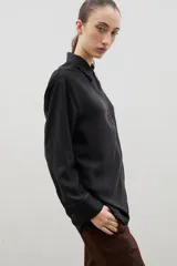 Camisa de corte holgado y diseño clásico, confeccionada en tela satinada con un sutil estampado floral tono sobre tono. Presenta cuello camisero, cierre frontal con botones y mangas largas con puños rectos.