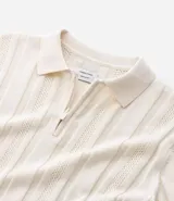 Camisa de punto color marrón con textura acanalada y perforaciones. Presenta cuello polo con cierre de cremallera frontal y mangas cortas.