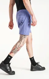 Short de baño color lavanda, de calce regular, con cintura elástica y cordón ajustable. Posee cuatro bolsillos, incluyendo bolsillos cargo con tapa en los laterales.