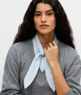 Suéter de punto gris con escote en V y detalle de camisa integrada en color celeste a rayas, con cuello estructurado y lazo frontal. Diseño de corte regular y mangas largas.