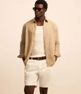 Bermuda básica color beige confeccionada en sarga de algodón, con trabillas en la cintura, cierre de botón y cremallera, y bolsillos laterales.