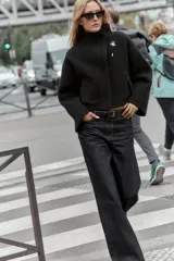 Chaqueta estilo bomber de punto color negro, con cuello subido, manga larga y cierre frontal cruzado con botones ocultos a presión. Presenta bolsillos delanteros de vivo.