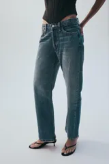 Jeans rectos de tiro medio en denim negro con efecto lavado. Presenta diseño de cinco bolsillos, trabillas para cinto y bajo con vuelta marcada. Cierre frontal con botones metálicos ocultos.