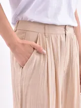 Pantalón de vestir color oliva, de corte amplio y tiro alto, con pinzas en la cintura y textura arrugada.