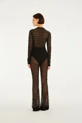 Pantalón acampanado de encaje negro con diseño transparente y tiro alto.