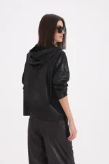 Campera con capucha de efecto engomado, con cierre frontal de botones, bolsillos delanteros y mangas largas.