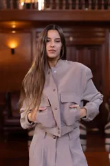 Chaqueta bomber color visón con cuello mao, cierre frontal con botones a presión, dos bolsillos de parche con solapa en el pecho, puños y cintura acanalados.
