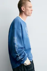 Camiseta de manga larga con cuello redondo y ajuste relajado. Presenta un efecto lavado, acabados en rib en cuello y puños, y un estampado frontal con el número 95 en contraste.