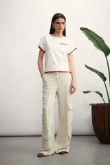 Remera blanca de manga corta con cuello redondo, bolsillo frontal y detalles de costura en color tostado en el bolsillo y los bordes de las mangas.