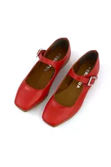 Zapato tipo Mary Jane color rojo, de cuero, con punta redondeada y tira sobre el empeine con hebilla metálica cuadrada.