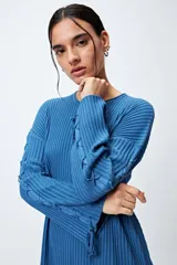 Sweater color crema de tejido de canalé con detalle de trenzado en las mangas y terminación con lazo ajustable.