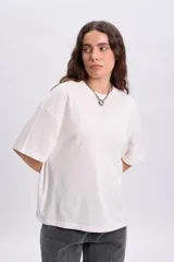 Remera manga corta texturada color crudo con parche bordado decorativo en la espalda.