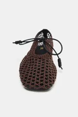 Zapato plano tipo bailarina marrón con diseño de calados en todo el cuerpo, terminación en punta cuadrada y cierre de lazo en la parte delantera.