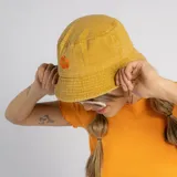 Gorro tipo bucket color azul con efecto lavado, que presenta un bordado blanco en el frente con la inscripción 'SUN DAY'.