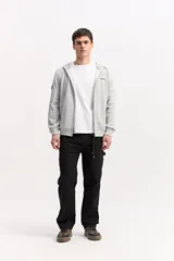 Campera de algodón gris melange con capucha, cierre frontal completo y bolsillos laterales. Cuenta con un parche rectangular negro con inscripciones en la manga y cordones ajustables para la capucha.