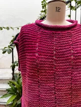 Chaleco tejido a mano en dos agujas con hilado 100% baby alpaca teñido artesanalmente, color magenta matizado. Diseño ligeramente oversize, de hombros anchos y cuello tipo bote, con puntos calados en frente y espalda y tajos a los lados en el bajo.