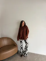 Pantalón Oxford tiro alto con estampado animal print de vaca en blanco y negro, de corte ajustado en la parte superior y acampanado en las botamangas.