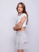 Minifalda negra con estampado de pequeñas flores, diseño de capas con volados y cintura elástica fruncida.