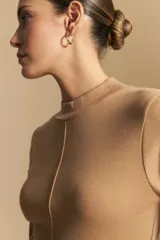 Polera de manga larga color marrón claro, con cuello alto y costura vertical decorativa en el frente.