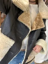 Campera de cuero genuino color marrón oscuro con interior y detalles de piel sintética en color crema. Cuenta con cierre frontal de botones, solapas amplias y puños con vuelta de piel.