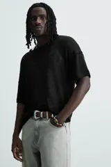 Camiseta de punto negro, corte relajado, con cuello redondo amplio y manga corta. El tejido es ligero y calado.