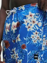 Short de baño azul marino con estampado de hojas de palmera azules y flores rojas.