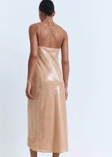 Vestido midi color beige, con diseño recto y escote halter con cierre de lazo en la espalda. El tejido principal es de lentejuelas.