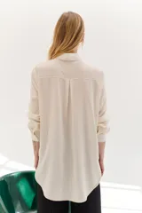 Camisa color crema de lyocell con cuello clásico, cierre frontal con botones, bolsillo de parche en el pecho y pespuntes a contraste en negro.