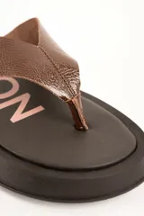 Sandalia tipo ojota Lemon de plataforma con base ancha negra y tira ancha de cuero marrón.