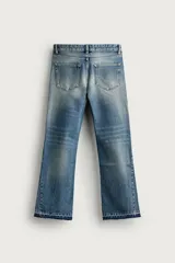 Jeans flare fit de denim de algodón en color celeste con lavado efecto desgastado. Presentan diseño de cinco bolsillos, tiro medio, cierre frontal con cremallera y botón, y bajo con acabado irregular.