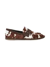 Mocasín de cuero con pelo vacuno en tonos marrón y blanco, con diseño clásico de antifaz y detalles fruncidos.