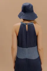 Vestido midi tejido de punto con diseño sin mangas y cuello halter. Presenta una silueta fluida con un panel de contraste en tono más claro a la altura de la cintura. Confeccionado con hilados italianos y sutiles toques de lurex.