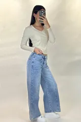 Pantalón de jean estilo wide leg con tiro alto, costuras verticales decorativas en el frente y corte diagonal en la parte inferior de las piernas.