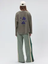 Pantalón de punto jacquard con diseño geométrico texturizado, de corte holgado y pierna ancha. Presenta tiro medio, cintura elástica con cordón ajustable y aberturas laterales en el ruedo.