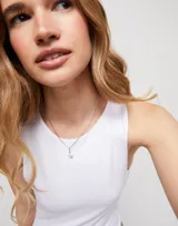 Dije charm plateado con una perla blanca colgante.