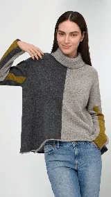 Polera de cuello alto confeccionada en lana lambswool, con diseño bicolor en negro y marrón. Presenta mangas largas con franjas verticales en gris y un parche circular bordado en la manga derecha.