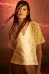 Blusa blanca con bordado inglés, escote en V, manga corta y cierre frontal con botones.