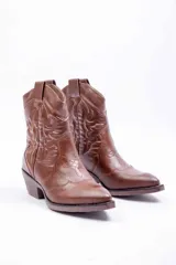 Bota texana de cuero sintético color marrón, con punta fina, taco bajo y costuras decorativas tradicionales en la caña.