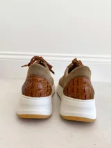 Championes de cuero color visón con cordones marrones, suela blanca y base color caramelo.