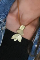 Collar con dije de bronce compuesto por piezas metálicas en forma de pétalos, suspendido de un tiento de cuero color tostado.