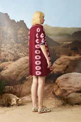 Vestido corto de tejido jacquard en color bordó con estampado de estrellas rosadas en los laterales. Presenta cuello polo con cierre frontal de botones y mangas cortas con terminación en contraste.